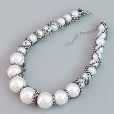 This Ivory Necklace offers sophisticated elegance with its gorgeous oversize resin pearls and twisted rhinestone chains, creating a timeless statement piece that elevates any ensemble - from casual to dressy - in an instant. Faux pearls constructed of resin, rhinestone chain 17 inches, 3 inches extended chain. PLEASE NOTE: DUE TO THE NATURE OF THIS NECKLACE, METAL WRAPED ON RESIN, THE FAUX PEARLS MAY HAVE MINOR SCRATCHES. THIS WILL NOT TAKE AWAY FROM THE BEAUTY OF THIS ITEM. JEWELRY IS NOT RETUR Elegant Rhinestone Necklace With Pearl Chain, Pearl White Necklace With Rhinestones, Elegant Pearl White Multi-strand Necklace, Luxury Gold-tone Pearl Chain Necklace, Ivory Necklace, Luxury Pearl White Multi-strand Necklace, Women's Jewelry Sets, Rhinestone Wedding, Charm Earrings