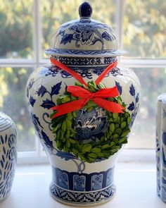 a blue and white vase with a red bow on it next to other ceramic containers