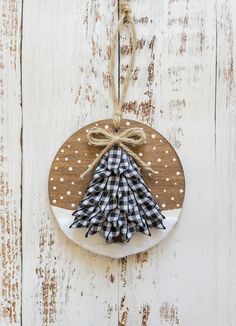 a wooden ornament with a christmas tree hanging from it's side on a white wood background