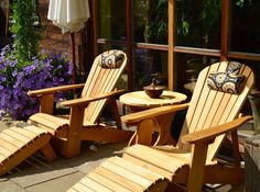 two wooden lawn chairs sitting next to each other on top of a stone patio area