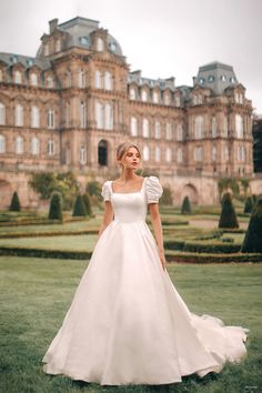 a woman in a white wedding dress standing in front of a large building