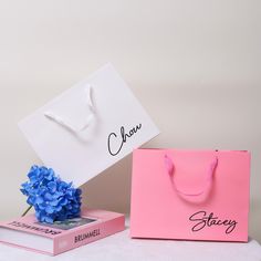 two bags with name tags on them sitting next to each other and blue hydrangeas