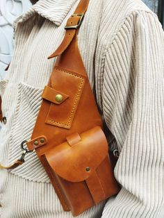 a man wearing a brown leather tie and holding a tan leather pouch on his shoulder