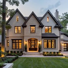 a large white house with lots of windows and lights on it's front porch