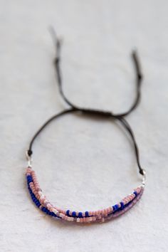 a close up of a beaded bracelet on a white surface with blue and pink beads