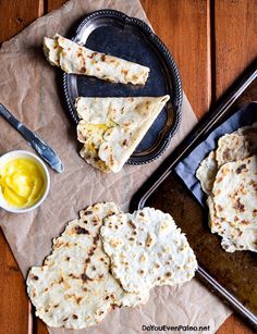 several flat breads are on a table with butter and mustard in the bowl next to them