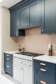 a kitchen with blue cabinets and white counter tops is pictured in this image, there are copper pulls on the stove