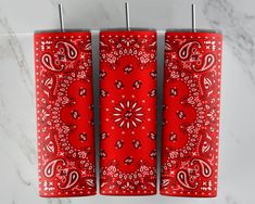 three red lighters with paisley designs on them sitting next to each other in front of a marble counter top