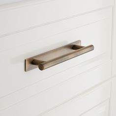 a close up of a door handle on a white cabinet