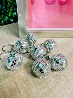 several disco ball keychains sitting on top of a table next to a vase