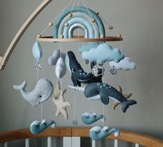 a baby crib mobile with sea creatures hanging from it's sides and clouds in the background