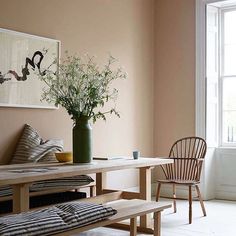 a vase with some flowers in it sitting on a table next to a chair and window