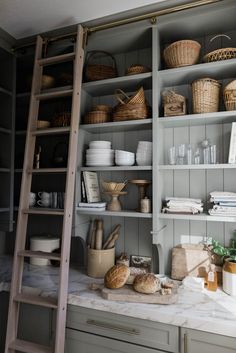 the shelves in this kitchen are filled with bread and other items, including baskets on them