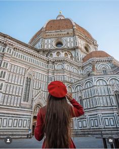 a woman wearing a red hat standing in front of a building