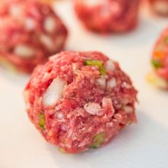 raw meatballs are sitting on a white surface