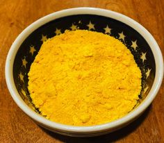 a bowl filled with yellow powder on top of a wooden table