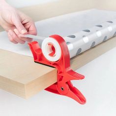 a person using a pair of pliers to cut paper on a piece of wood