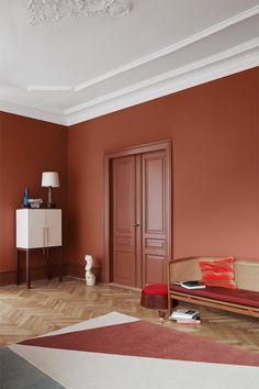 a living room with red walls and wooden floors, an orange couch and white cabinet