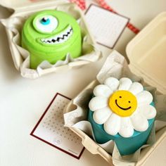 two cupcakes decorated to look like monsters with faces on them and flowers in the middle