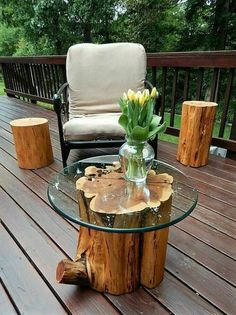 a glass table with flowers on it sitting on a wooden deck next to a chair