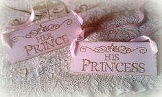 two pink princess signs sitting on top of a white lace covered tablecloth next to each other