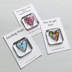 three magnets with hearts on them sitting next to each other in front of a card