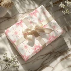 a pink and white gift box with a bow on it sitting on a marble surface