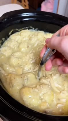 a person using a fork to stir food in a crock pot