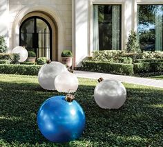 two large blue and white balls sitting on top of a lush green field next to a building