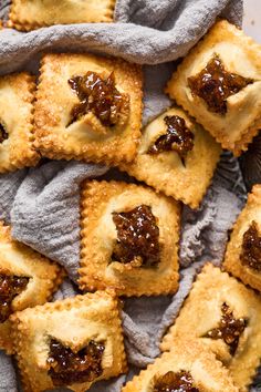 small pastries with jam on them sitting on top of a cloth next to a basket