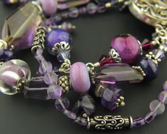 "If you love purple, this is the bracelet for you! This triple strand bracelet is designed with sterling silver, handmade glass beads in a variety of purples, faceted amethyst gemstones, and Swarovski crystals. Sterling silver chain and dangles add a fun touch. (I suggest wearing that strand on the outside toward your fingers to show off the dangles!) A stunning decorative sterling silver box clasp completes the design.  This luscious new bracelet will fit a 6 1/2\" to 7\" wrist. Your bracelet w Handmade Purple Sterling Silver Beaded Bracelets, Spiritual Purple Jewelry With Unique Variations, Artisan Purple Bracelet Jewelry, Purple Double Strand Jewelry For Gifts, Purple Sterling Silver Beaded Bracelets With Round Beads, Artisan Purple Round Bead Jewelry, Artisan Purple Round Beaded Jewelry, Purple Polished Bead Bracelet Jewelry, Purple Czech Glass Beaded Bracelets With Spacer Beads