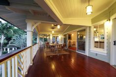 a porch with wood flooring and white trim on the walls, along with an outdoor dining area