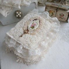 an old box is adorned with pearls and lace, along with other vintage jewelry items