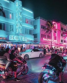 several motorcycles parked on the street in front of a building with neon lights at night