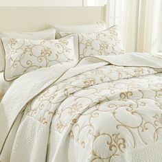 a bed with white and gold comforters in a bedroom