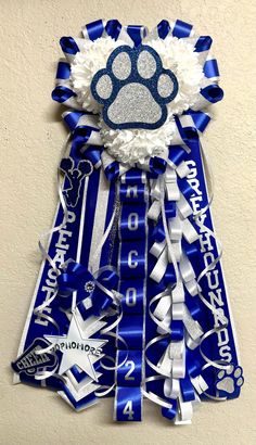 a blue and white ribbon with a paw print on the front is attached to a wall