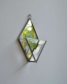 a triangle shaped mirror hanging on the side of a wall next to a white wall