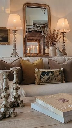 a living room filled with lots of furniture next to a mirror and candles on top of a table