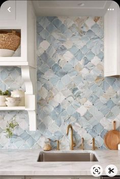 a kitchen with blue and white tile backsplashing, gold faucet