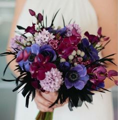 a bride holding a bouquet of purple flowers