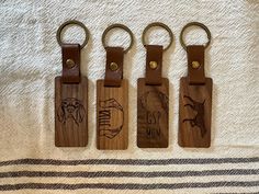 three wooden keychains with different designs on them sitting on a towel next to each other