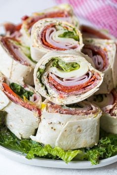 a white plate topped with lots of different types of wraps on top of lettuce