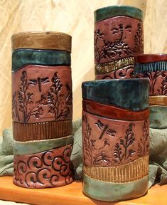 four different colored vases sitting on top of a wooden table next to each other