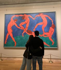 two people standing in front of a large painting on display at an art museum,