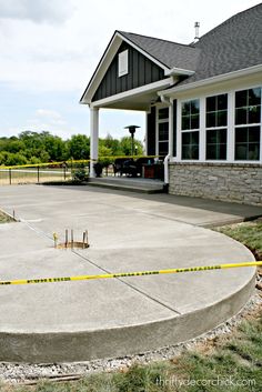 a concrete patio with yellow caution tape around it and a large house in the background