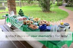 a picnic table with food and drinks on it in front of a park bench that says protect more of your memories for less