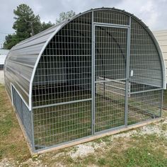 a large chicken coop in the grass next to a building