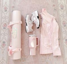 the contents of a woman's pink outfit laid out next to a travel mug