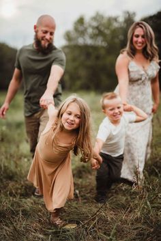 a family playing in the grass with their toddler and older child smiling at the camera