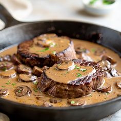 two steaks with mushrooms and gravy in a skillet